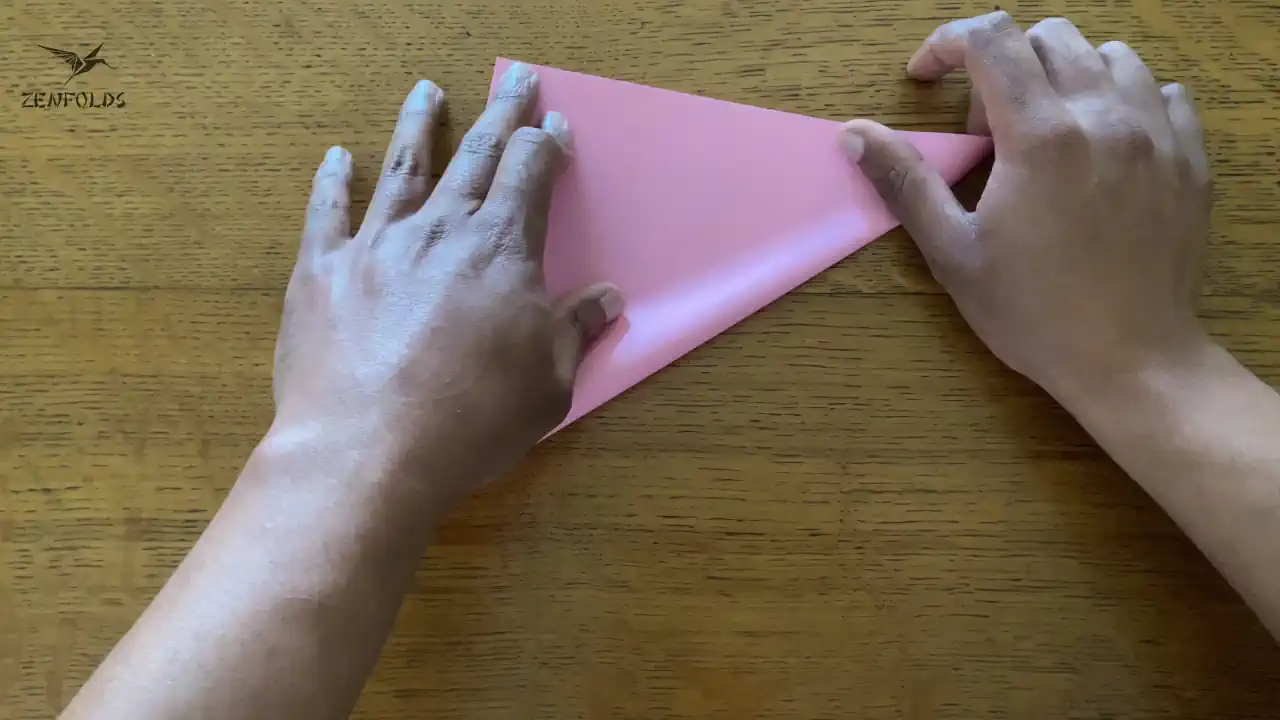 pink square origami sheet folded in half