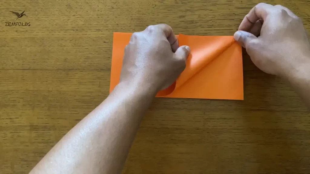 orange square origami sheet of paper with right edge folded