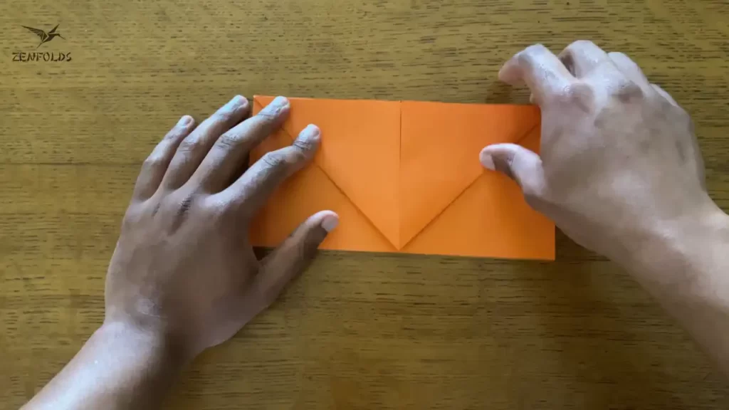 orange square origami sheet of paper with both edges folded