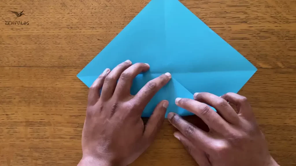 blue square origami sheet of paper being folded into a blintz base