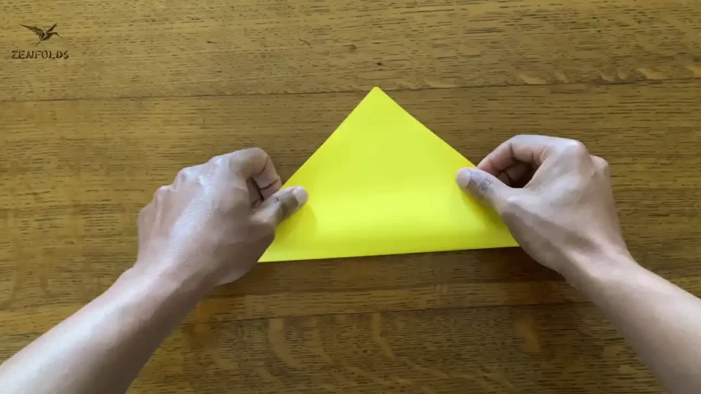 yellow square origami sheet of paper folded in half diagonally