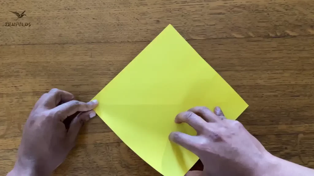 yellow square origami sheet of paper with a diagonal crease.