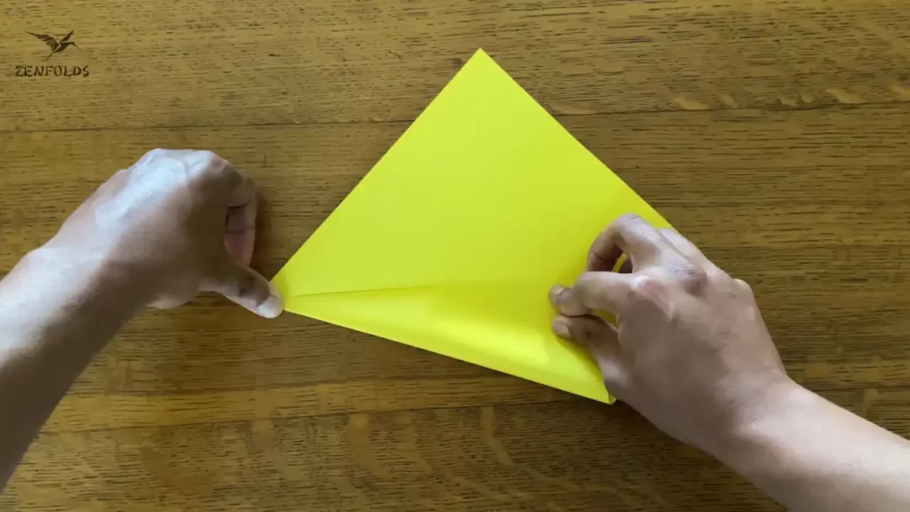 yellow square origami sheet of paper with the lower left edge folded along a diagonal crease